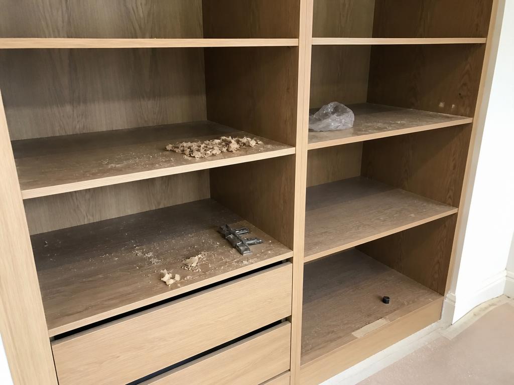 Sawdust and carpentry debris on shelves of a newly installed wardrobe